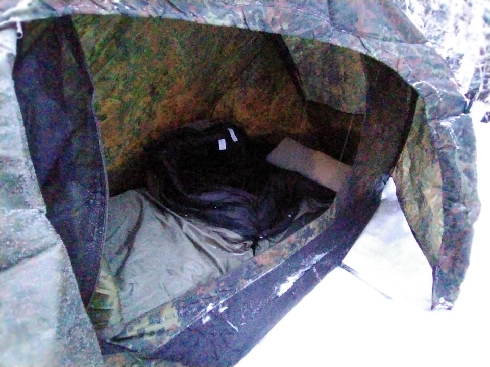 Inside of the tent, with a sleeping bag and a mattress. 